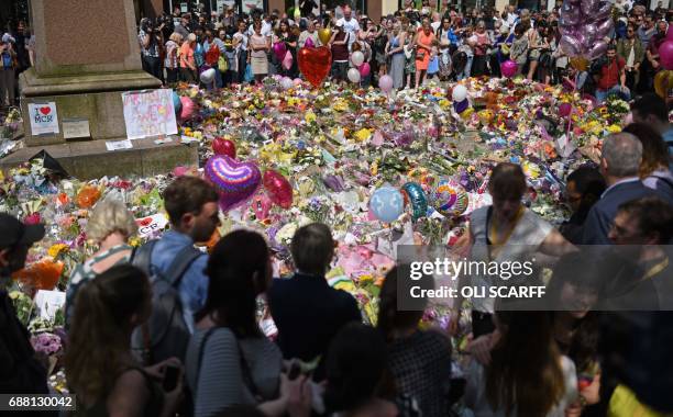 People stop by a mass of flowers to observe a minute's silence in St Ann's Square in Manchester, northwest England, on May 25 as a mark of respect to...