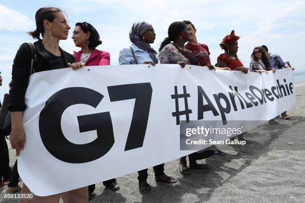 Participants in a gathering of NGOs meeting to discuss relevant issues around the G7 Taormina summit hold a banner on the beach near the G7 media...