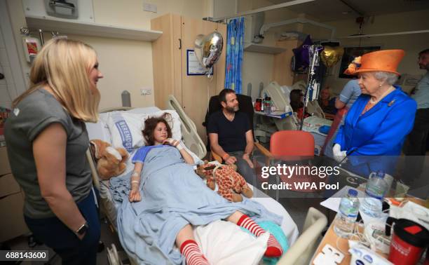 Queen Elizabeth II speaks to Evie Mills from Harrogate, her mother, Karen and dad, Craig, during a visit to the Royal Manchester Children's Hospital...