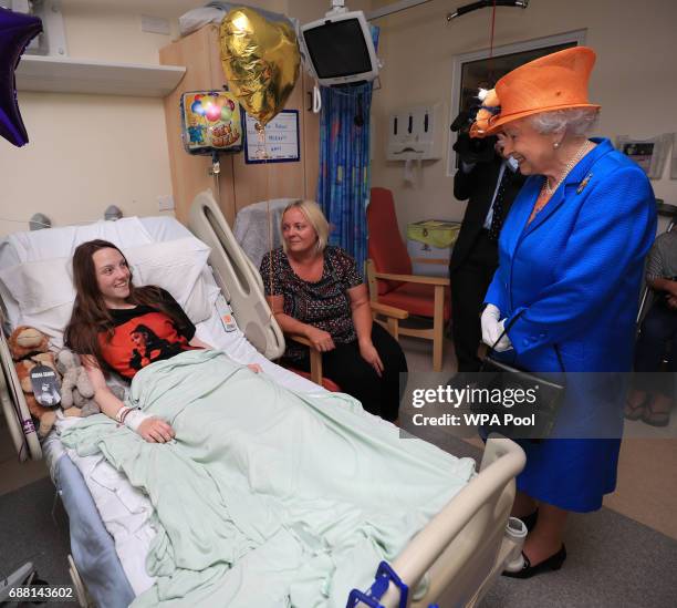 Queen Elizabeth II speaks to Millie Robson from Co Durham, and her mother, Marie, during a visit to the Royal Manchester Children's Hospital to meet...