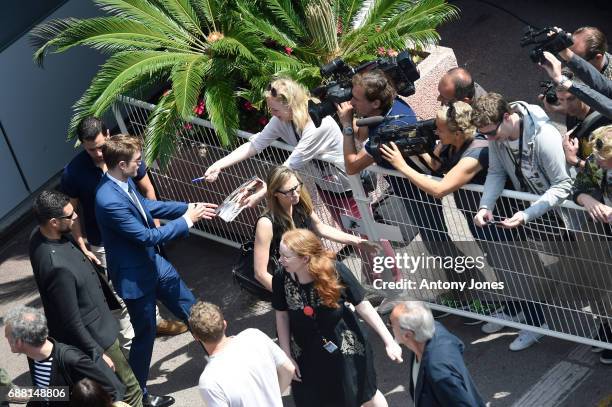 Actor Robert Pattinson leaves the Palais des Festivals after the "Good Time" press conference and signs autographs for fans during the 70th annual...