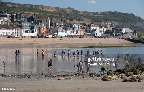 People paddle in the sea as they enjoy the warm weather on the beach in Lyme Regis on May 25, 2017 in Dorset, England. Parts of the UK are currently...