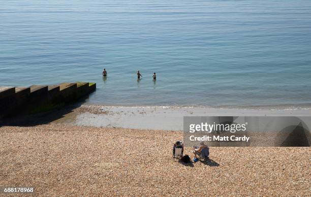 People paddle in the sea as they enjoy the warm weather on the beach in Lyme Regis on May 25, 2017 in Dorset, England. Parts of the UK are currently...