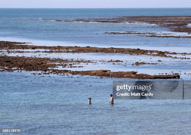 People paddle in the sea as they enjoy the warm weather on the beach in Lyme Regis on May 25, 2017 in Dorset, England. Parts of the UK are currently...