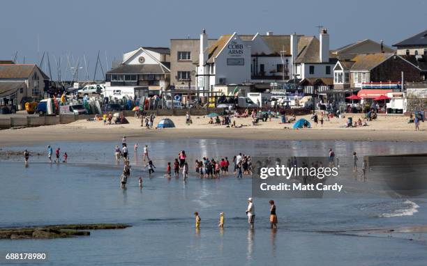 People paddle in the sea as they enjoy the warm weather on the beach in Lyme Regis on May 25, 2017 in Dorset, England. Parts of the UK are currently...