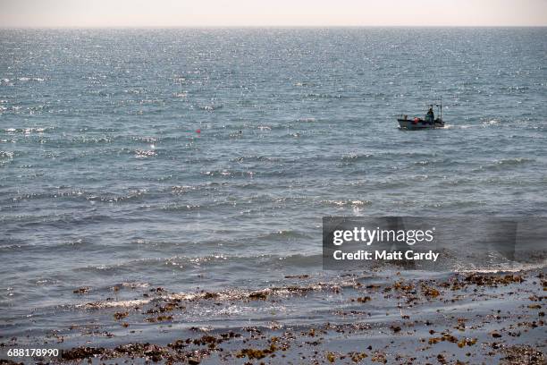 Man fishes from a boat out at sea as he enjoys the warm weather in Lyme Regis on May 25, 2017 in Dorset, England. Parts of the UK are currently...