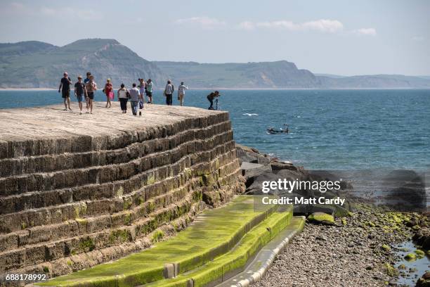 People walk around the harbour as they enjoy the warm weather on the beach in Lyme Regis on May 25, 2017 in Dorset, England. Parts of the UK are...