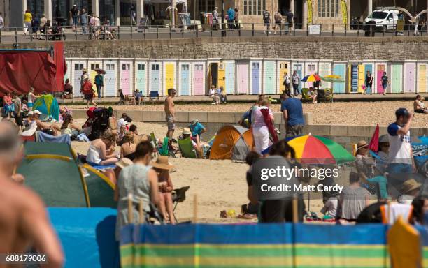 People sit on the beach as they enjoy the warm weather on the beach in Lyme Regis on May 25, 2017 in Dorset, England. Parts of the UK are currently...