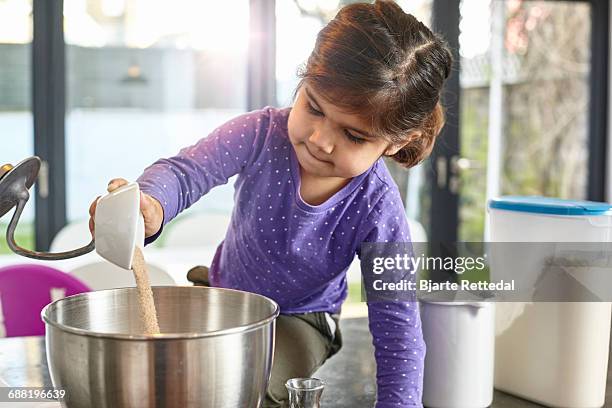 girl pouring sugar into mixing bowl - bjarte rettedal stock pictures, royalty-free photos & images
