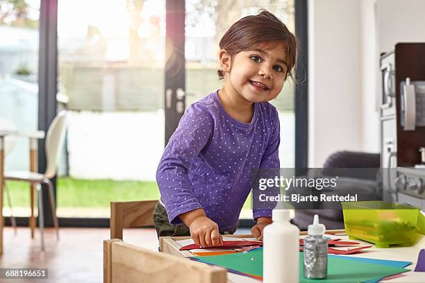 girl smiling to camera while making craft animals - bjarte rettedal stock pictures, royalty-free photos & images