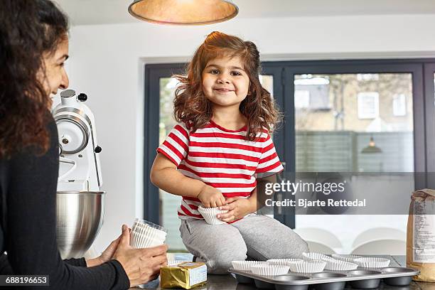 little girl helping mum making cupcakes - bjarte rettedal stock pictures, royalty-free photos & images