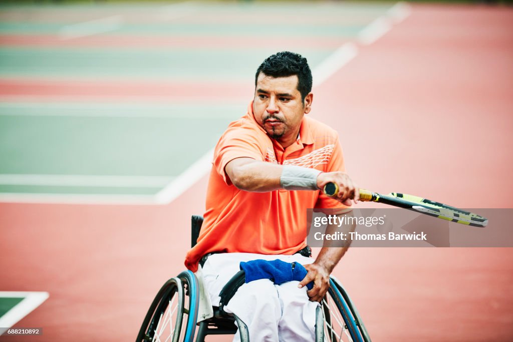 Adaptive athlete preparing for backhand shot during wheelchair tennis match