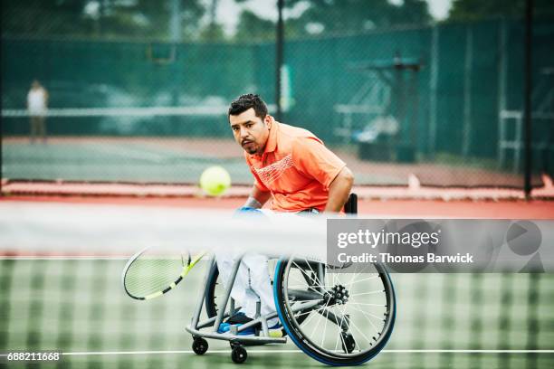 Adaptive athlete chasing down shot during wheelchair tennis match