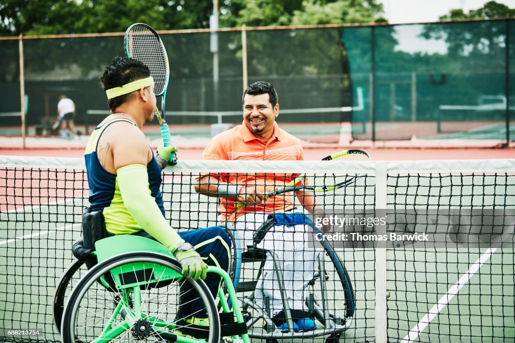 Smiling adaptive athletes at net after wheelchair tennis match