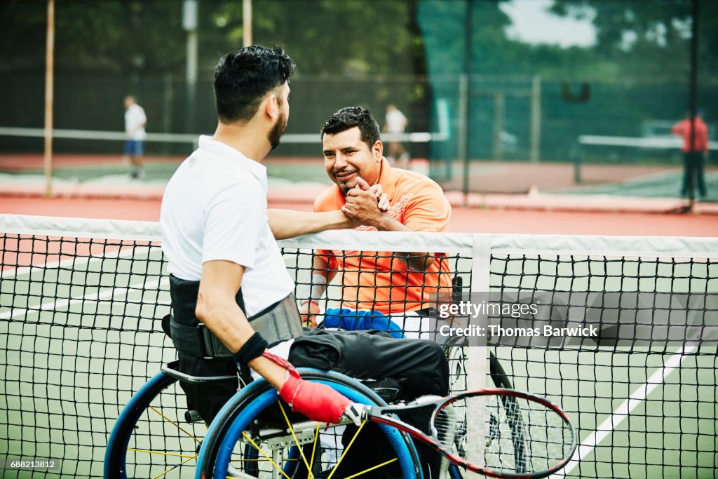 Adaptive athletes shaking hands at net after wheelchair tennis match