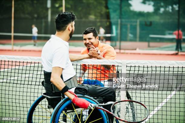 Adaptive athletes shaking hands at net after wheelchair tennis match