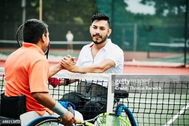 Adaptive athletes shaking hands and congratulating each other after wheelchair tennis match