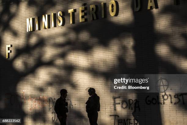 The silhouettes of federal army soldiers are seen standing guard outside the vandalized Treasury Ministry building in Brasilia, Brazil, on Thursday,...