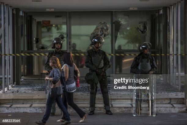 Pedestrians pass in front of federal army soldiers standing guard outside the vandalized Treasury Ministry building in Brasilia, Brazil, on Thursday,...