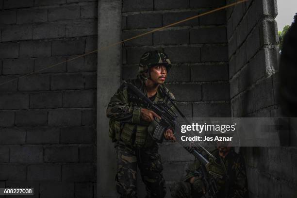 Soldiers take positions while evading sniper fire as they try to clear the city of armed militants one street at a time, on May 25, 2017 in Marawi...