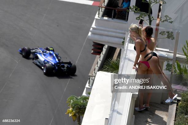 Women look on as Sauber's German driver Pascal Wehrlein steers his car during the second practice session at the Monaco street circuit on May 25,...