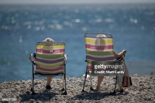 People sit beside the sea as they enjoy the fine weather on the beach in Lyme Regis on May 25, 2017 in Dorset, England. Parts of the UK are currently...