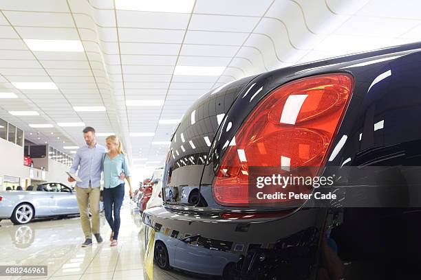 couple walking through car showroom - polish car stock pictures, royalty-free photos & images