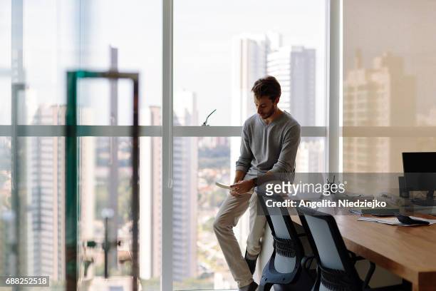 young man sitting on the table with view of the city in the background - city book stock pictures, royalty-free photos & images