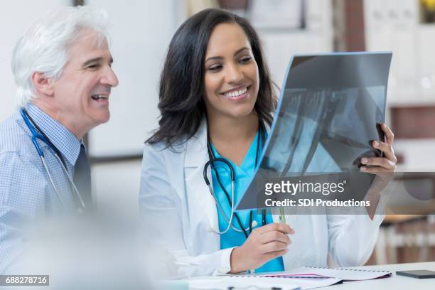 自信を持って多様な医師は、患者さんの x 線��を確認します。 - orthopedic surgeon ストックフォトと画像