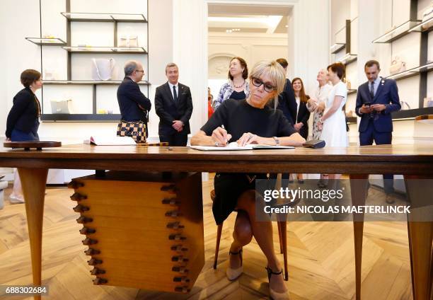 Brigitte Macron, wife of French President, signs a guestbook during a visit of the First Ladies to a shop of Belgian fashion label Delvaux, on May 25...