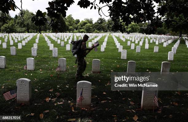 Members of the 3rd U.S. Infantry Regiment place flags at the headstones of U.S. Military personnel buried at Arlington National Cemetery, in...