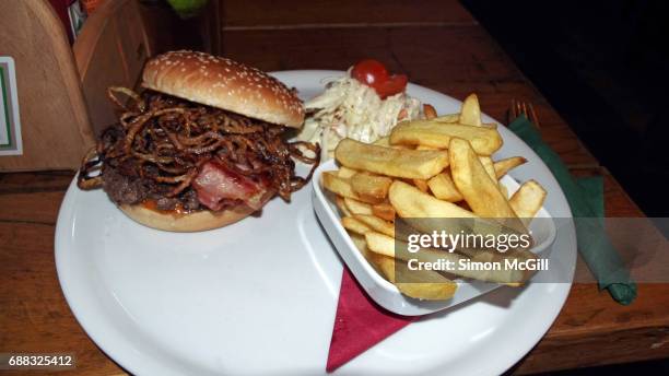 beef hamburger with bacon and fried onion rings, served with potato chips and coleslaw at a pub in prague, czech republic - kneipengericht stock-fotos und bilder