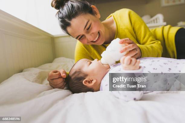 mother feeding baby with bottle - milchflasche stock-fotos und bilder