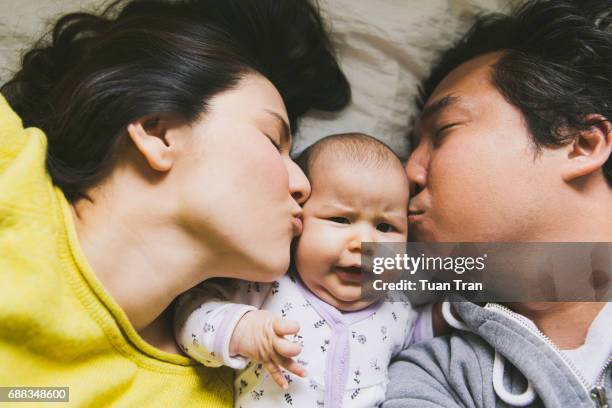 parents kissing baby - baby close up bed stockfoto's en -beelden