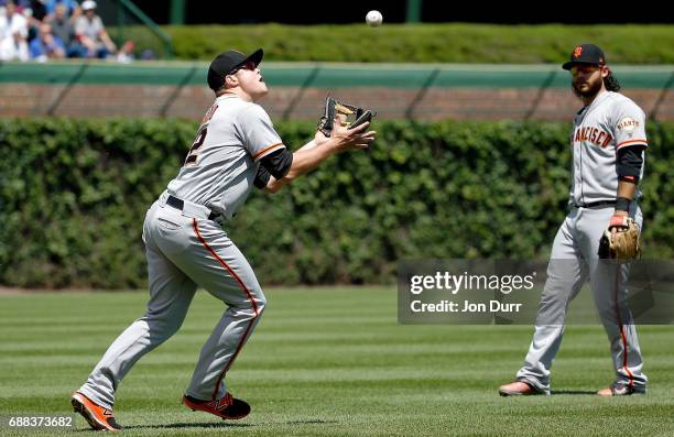 Christian Arroyo of the San Francisco Giants makes a catch for an out against the Chicago Cubs as Brandon Crawford looks on during the second inning...