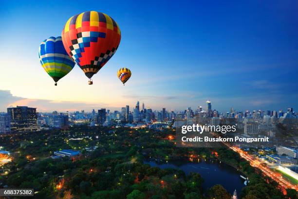 hot air balloons fly over cityscape at sunset background - ballon festival stock-fotos und bilder