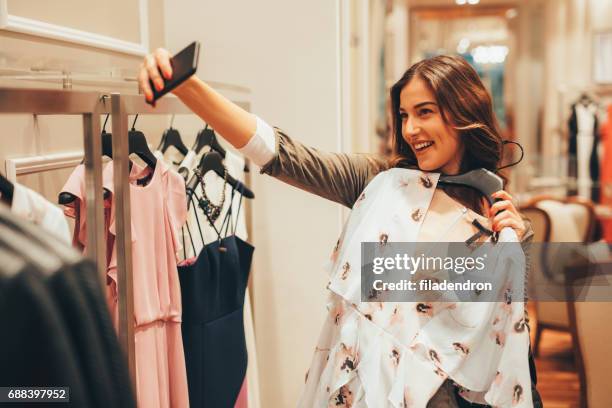 woman taking a selfie with a blouse in a clothing store - woman's blouse stock pictures, royalty-free photos & images