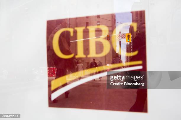 Pedestrians are reflected in Canadian Imperial Bank of Commerce signage on a building in Toronto, Ontario, Canada, on Friday, May 19, 2017. Ontario...