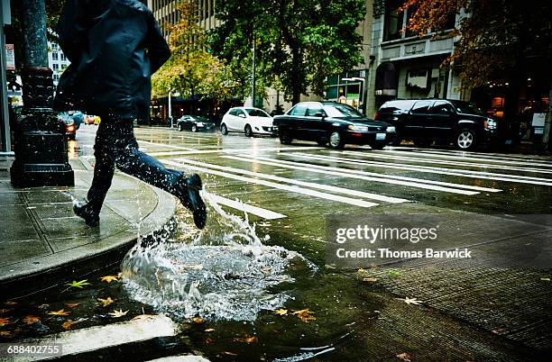 businessman jumping through puddle on city street - flaque photos et images de collection