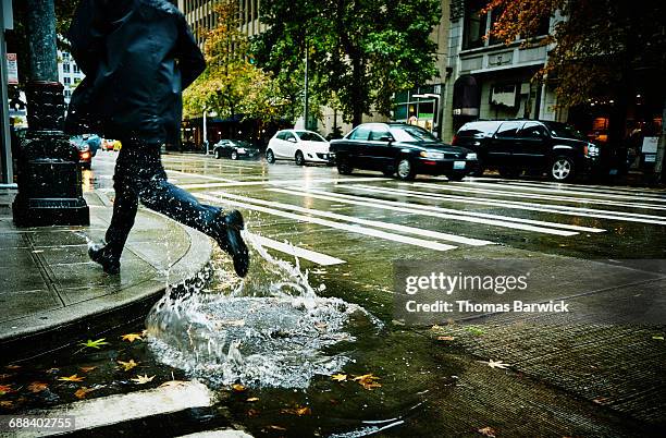 businessman jumping through puddle on city street - poça imagens e fotografias de stock