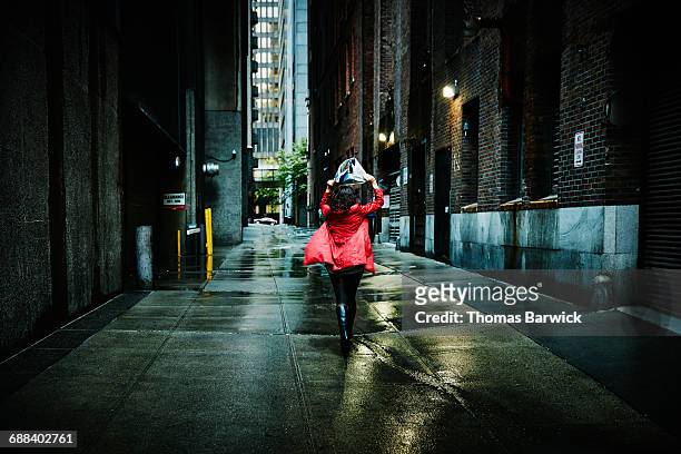businesswoman running down alley in rain storm - first exposure series stock pictures, royalty-free photos & images