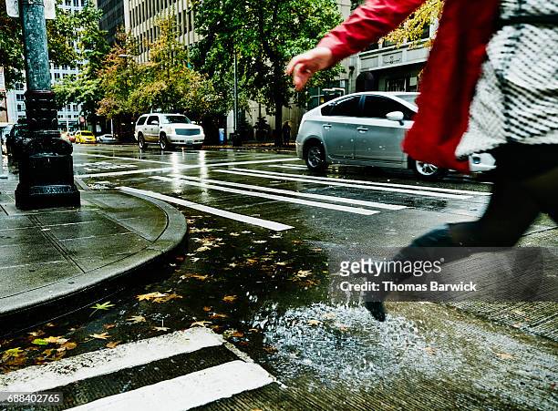 businesswoman jumping over puddle on city street - puddle foto e immagini stock
