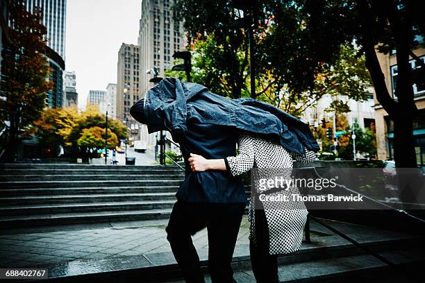 couple running up stairs with coat over head - rain couple stockfoto's en -beelden