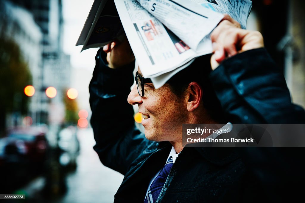 Businessman using newspaper to protect from rain