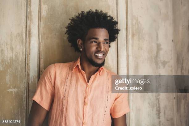 handsome afro-caribbean cuban man leaning on wooden wall - peach colour stock pictures, royalty-free photos & images