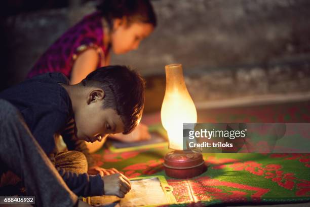 garçon et fille écrit sur l’ardoise sous la lampe à huile - children oil lamp study photos et images de collection