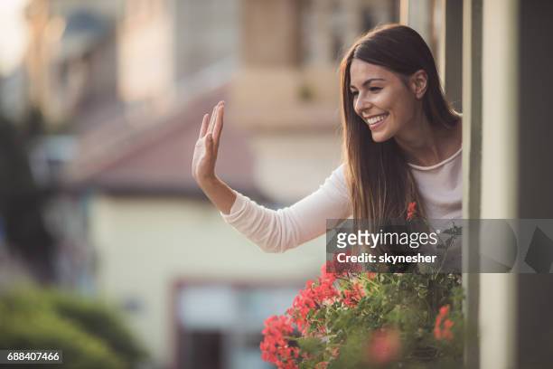 bella donna che saluta qualcuno per strada dalla finestra della sua casa. - sventolare la mano foto e immagini stock