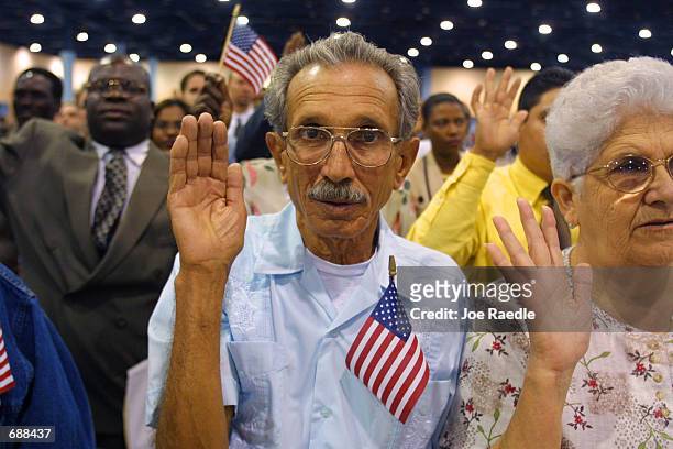Pedro Pablo Machado and Maria Arias, both natives of Cuba, raise their right hands as they are sworn in as new U.S. Citizens December 19, 2001 in...