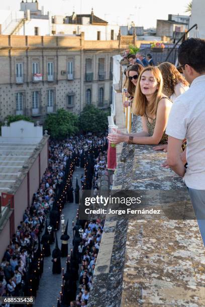 People watching a procession from the top of a building while enjoying the good weather and a few drinks.