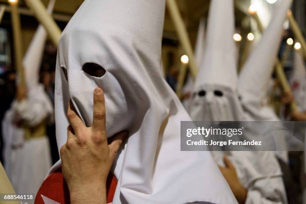 Nazarenos participating in a religious procession, with the traditional robes and hoods and carrying candles during Semana Santa in Seville.